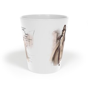 May include: A white ceramic mug featuring a fashion illustration of a person in a flowing tan dress. The text reads: She is clothed in strength and dignity she laughs without fear of the future Proverbs 31:25. The design uses soft brown and tan tones.