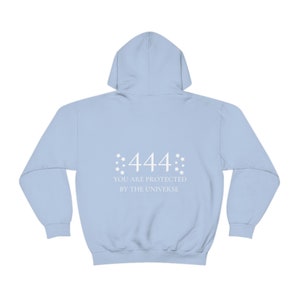 Könnte beinhalten: Hellblauer Kapuzenpullover mit dem Aufdruck "444 You are protected by the universe" auf der Rückseite.