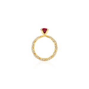 May include: A gold ring with a red gemstone and a twisted band of diamonds.