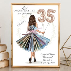 May include: A framed print featuring a woman in a dress made of money, holding two "35" balloons. The print includes German text wishing a happy birthday and a message, "May all your dreams and wishes come true!"