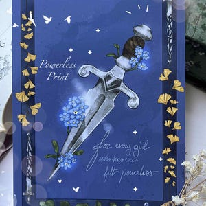 Peut inclure: Une affiche bleue avec une illustration de poignard argenté, ornée de fleurs bleues et de feuilles dorées. Le texte "Powerless Print" et "for every girl who has ever felt powerless" sont présents.