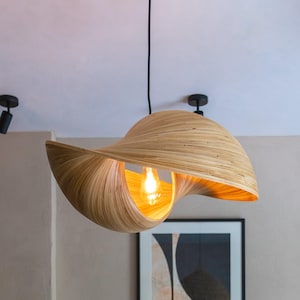 May include: A modern, wooden pendant light with a unique, curved design. The light is made of natural bamboo and features a warm, incandescent bulb.