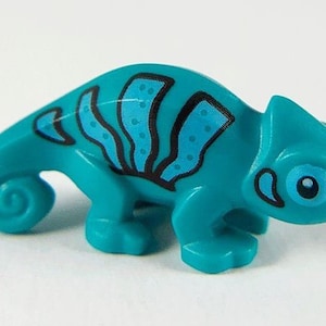 Op de afbeelding: Een turquoiseblauw kameleon speelgoed met zwarte en blauwe markeringen. De kameleon heeft een gekrulde staart en een groot, rond oog.