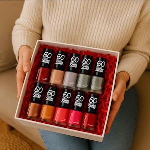 May include: A gift box containing twelve bottles of nail polish in a range of colours, including red, orange, pink, and neutral shades. Each bottle is labelled with the number "60" and "Super Shine". The box is lined with red decorative filler.