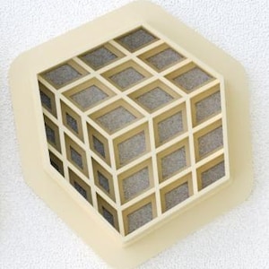 May include: A beige hexagonal wall sculpture with a 3D geometric design. The sculpture is made of a light beige material and features a pattern of squares and rectangles.