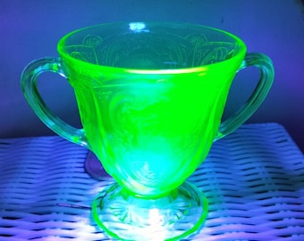 Uranium glass goblet with two handles and intricately etched design