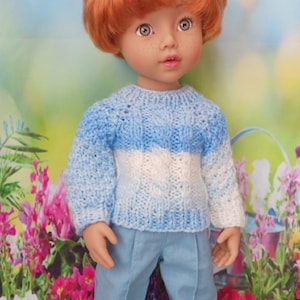 May include: A doll dressed in a light blue and white sweater and matching light blue pants. The doll has red hair and white shoes. The background features flowers and a blue sky.