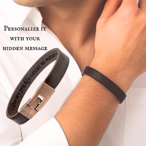 Puede incluir: Una pulsera de cuero marrón oscuro con un cierre metálico y un grabado interior que dice "I love my prickly catcus no matter what". El texto "PERSONALIZE IT WITH YOUR HIDDEN MESSAGE" aparece sobre la pulsera.