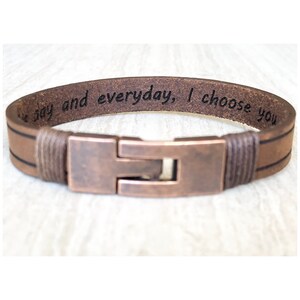 Può includere: Bracciale in pelle marrone con chiusura color rame. Il bracciale ha il testo inciso "the day and everyday, I choose you". Il bracciale è una semplice fascia con chiusura rettangolare.