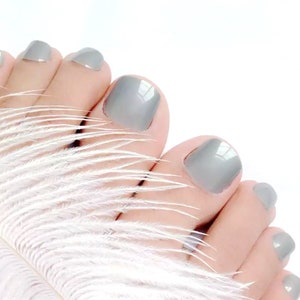 May include: Close-up of a foot with gray nail polish on the toes.
