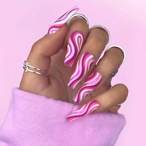 May include: Pink and white swirl patterned long false nails. The nails are long and have a square shape.