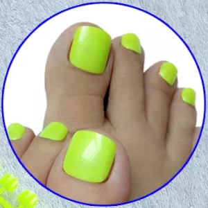 May include: Close-up of a foot with bright neon yellow nail polish on the toes.