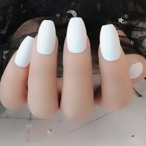 May include: A set of white coffin-shaped false nails. The nails are all the same size and shape, and they have a smooth, matte finish.