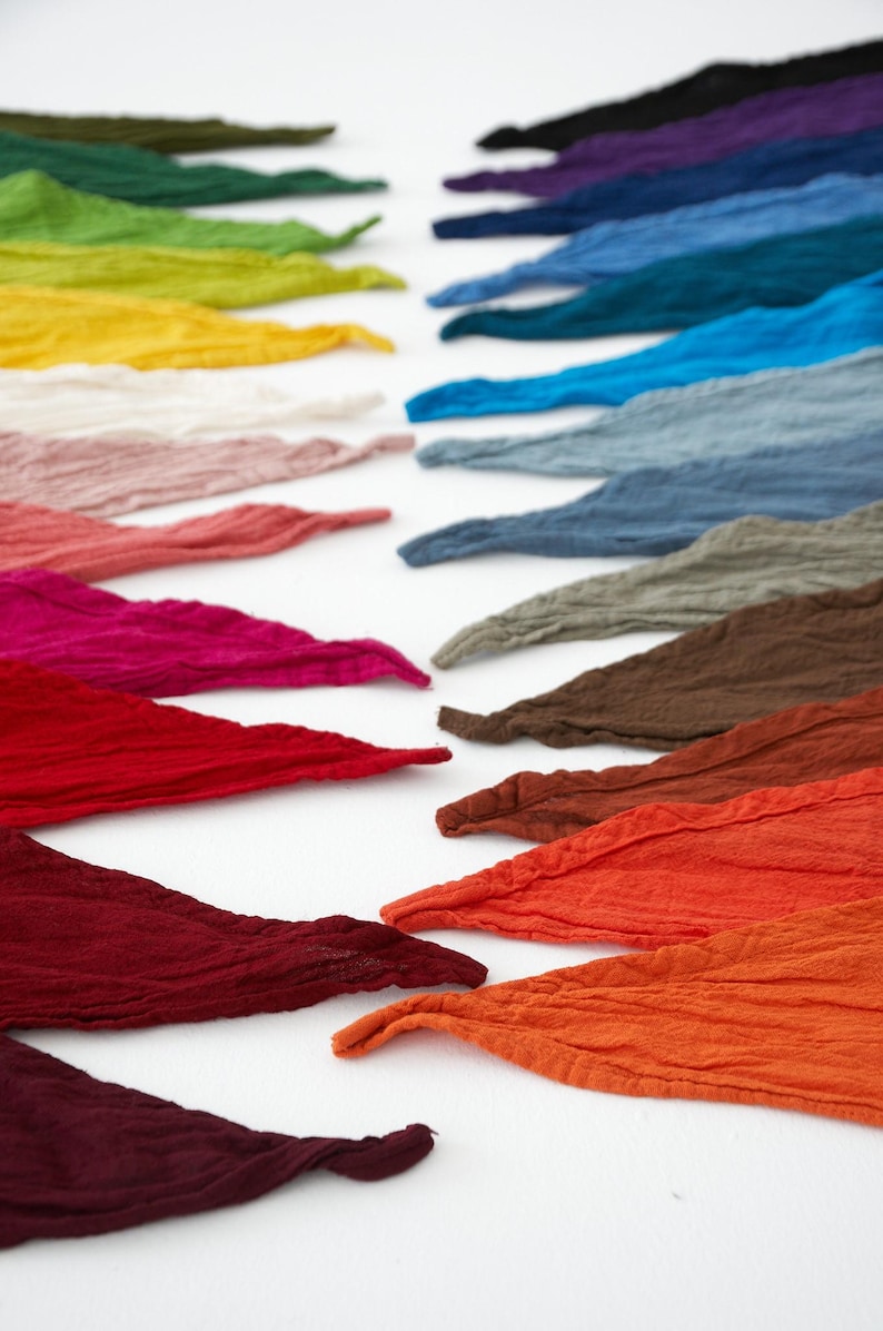 K&ouml;nnte beinhalten: Reihen farbiger Stoffstreifen in verschiedenen Farbt&ouml;nen. Die Streifen zeigen ein Spektrum an Farben, darunter Gr&uuml;n, Gelb, Rosa, Rot, Blau und Braun. Der Stoff hat eine strukturierte Optik und die Anordnung erzeugt eine ansprechende visuelle Darstellung.