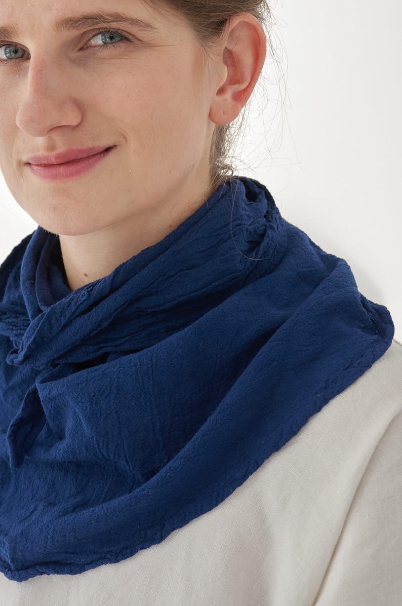 K&ouml;nnte beinhalten: Nahaufnahme einer Person, die einen dunkelblauen Schal tr&auml;gt. Der Schal besteht aus einem strukturierten Stoff und ist um den Hals drapiert. Die Person tr&auml;gt ein helles Hemd.