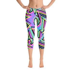 May include: A pair of black leggings with a colorful geometric pattern. The pattern includes pink, blue, yellow, and black shapes and lines.