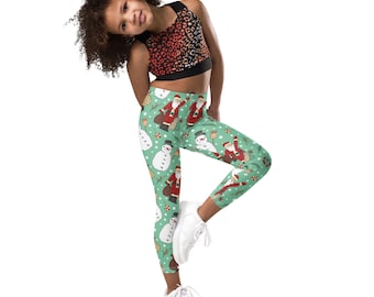 May include: Green leggings with a Christmas pattern featuring Santa Claus and snowmen. The leggings are worn by a young person with curly hair wearing a leopard print tank top.