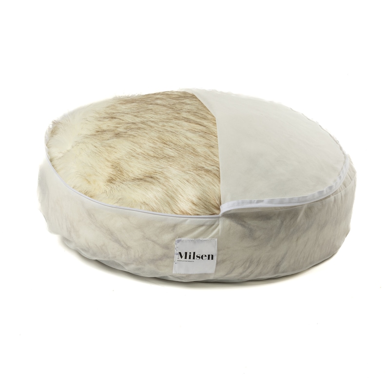 May include: A round, cream-colored dog bed with a removable faux fur insert. The bed has a white label with the word "Milsen" printed on it.