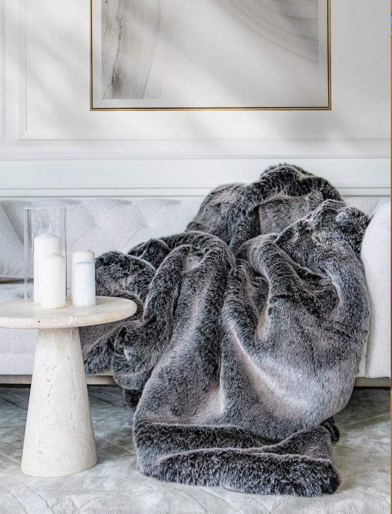 Luxurious faux fur throw in sophisticated shades of grey merges comfort with elegance, making it the perfect addition to your home decor. This soft, warm throw enhances the ambiance of your living room and bedroom with a modern design and inviting atmosphere. Its exclusive design and plush faux fur finish offer a versatile choice for lovers of elegant, glamorous, and minimalist home styling. This faux fur blanket is your investment in unmatched comfort, elegance, and luxury for your home.