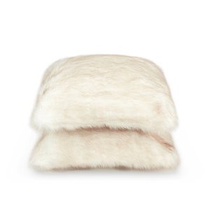 Luxurious set of two faux fur pillows in warm cream tones perfectly complements soft blankets to create a unique interior arrangement. These elegant home decor accents highlight comfort and sophistication, giving a distinctive touch to alcoves, bedrooms, living rooms, and relaxation spaces. Add a designer accent of luxury and warmth to your home.