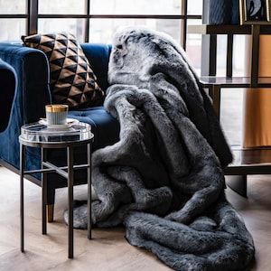 Luxury Graphite Furry Blanket 
Discover our designer furry blanket in captivating graphite and black tones, perfectly designed to enhance your glamorous and modern home decor. Its ultra-soft texture not only infuses your living room or bedroom with warmth and comfort but also serves as a unique decorative accent that highlights elegance and luxury in every setting. Ideal for home decor enthusiasts who value comfort and style, this fur blanket is a practical and chic addition for cool evenings.