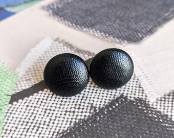 May include: A pair of black stud earrings with a textured surface.