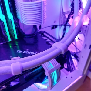 May include: A close-up of a computer case with white and green cables. The case is lit with purple and blue lights. The text "TUF GAMING" is visible on the motherboard.