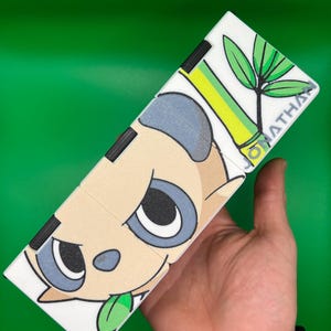 May include: A white, segmented puzzle featuring a panda design with black, gray, and tan colors. The panda has a green leaf in its mouth and is set against a green background. The name "JONATHAN" is printed on the puzzle.