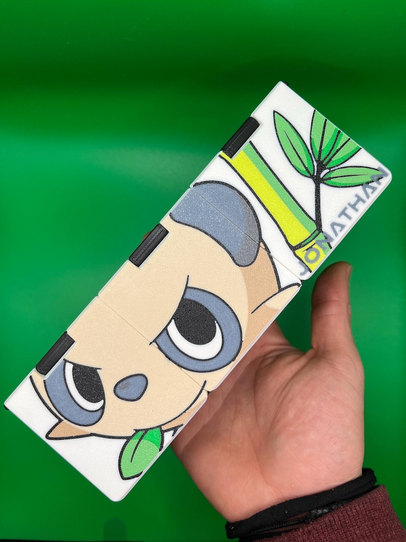 May include: A white, segmented puzzle featuring a panda design with black, gray, and tan colors. The panda has a green leaf in its mouth and is set against a green background. The name "JONATHAN" is printed on the puzzle.