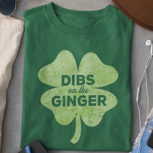 May include: Green t-shirt featuring a four-leaf clover design and the text "DIBS on the GINGER".