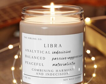Könnte beinhalten: Eine braune Sojawachskerze in einem durchsichtigen Glasgefäß mit einem weißen Etikett. Das Etikett lautet "THE SIBLING CO. LIBRA ANALYTICAL indecisive BALANCED passive-aggressive PEACEFUL materialistic COMBINING HARMONY AND INDECISION. 9 OZ (G) SOY WAX CANDLE".