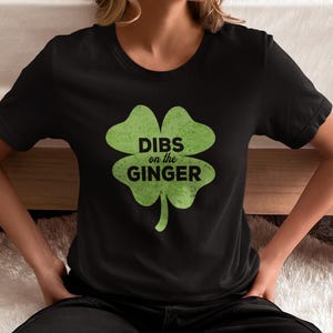 Może przedstawiać: Czarny T-shirt z zielonym nadrukiem koniczyny czteroliściennej i tekstem "DIBS on the GINGER".