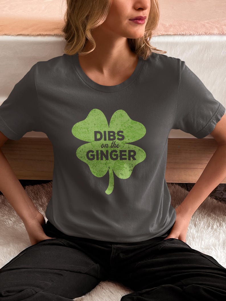 Może przedstawiać: Szary t-shirt z zielonym nadrukiem koniczyny czteroliściennej. Koniczyna zawiera napis "DIBS on the GINGER" wewnątrz.