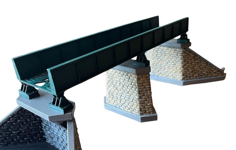 May include: A model train bridge with a green metal structure and stone supports. The bridge is designed for use with model train sets.