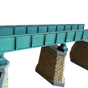 May include: A model train bridge made of green metal with brick supports. The bridge is designed for use with model train sets.