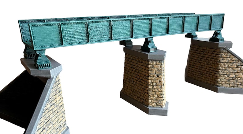 May include: A model train bridge with a green metal structure and stone supports. The bridge is made of plastic and is designed for use with model trains.
