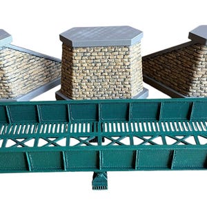 May include: Three brick abutments with a green metal bridge in between. The bridge has a lattice design and is made of metal.