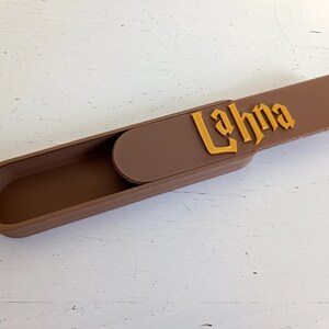 Op de afbeelding: Een bruine, rechthoekige doos met een schuifdeksel. Het deksel heeft de tekst "Lahna" in gouden letters.