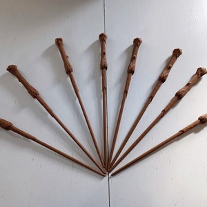 Peut inclure: Sept baguettes marron sont disposées en éventail sur une surface blanche. Chaque baguette a une poignée texturée et un corps fin et effilé. Les baguettes semblent être faites de bois ou d'un matériau similaire, et elles sont toutes de la même couleur.
