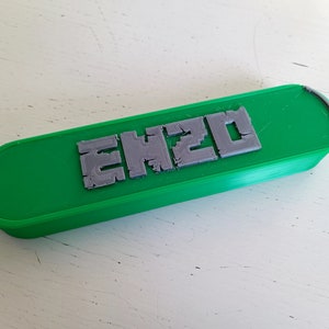 Op de afbeelding: Een groene plastic behuizing met het woord "EH20" in grijze letters gegraveerd.