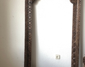 Peut inclure: Un grand cadre en bois sculpté de manière complexe avec une ouverture en arc. Le cadre est brun foncé et présente un motif floral.