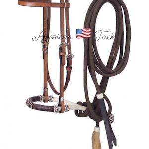 Puede incluir: Bridón de caballo de cuero marrón con rienda de cuerda trenzada. La rienda de cuerda tiene un patrón blanco y marrón y un borla de cuero marrón.