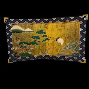 Könnte beinhalten: Japanische Stellwand mit goldenem Hintergrund und detaillierter Landschaftsszene. Das Kunstwerk zeigt einen Kranich, Bäume und einen Berg. Der Bildschirm ist mit einem dunkelblauen Rahmen mit floralen Mustern versehen.