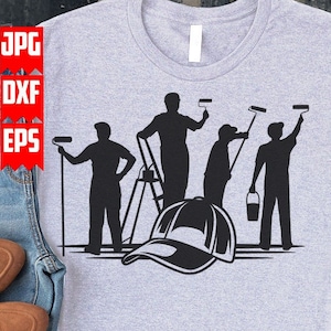 Puede incluir: Una camiseta gris con una silueta negra de cuatro pintores que sostienen rodillos de pintura y un cubo de pintura. Una gorra de béisbol negra está en el centro del diseño.