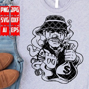 May include: Black and white illustration of a cartoon character wearing a hat and smoking a cigarette. The character is holding a bag of money and a wad of cash. The background is a grey t-shirt.