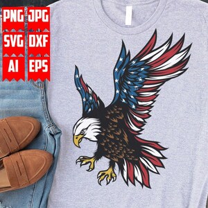 May include: A gray t-shirt with a graphic of a bald eagle with its wings spread. The eagle's wings are decorated with the American flag.