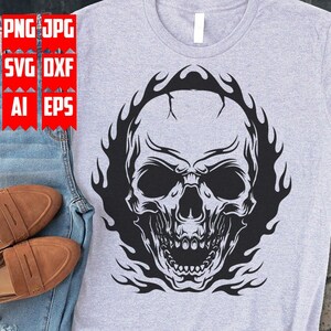 May include: A gray t-shirt with a black and white graphic of a skull with flames behind it.