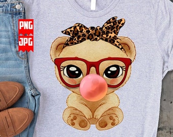 May include: A gray t-shirt with a cartoon illustration of a brown bear wearing red glasses and a leopard print headband. The bear is blowing a pink bubble.
