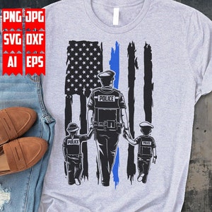 以下が含まれることがあります： 青いラインが入ったアメリカ国旗の前に、警官と子供2人が歩いているデザインのグレーのTシャツ。警官と子供たちの制服には「Police」の文字が書かれている。