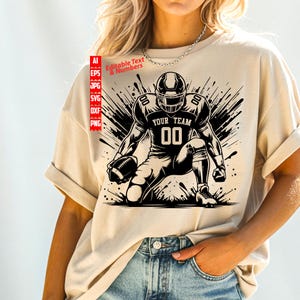 May include: Beige t-shirt featuring a black and white illustration of a football player kneeling with a football. The text "YOUR TEAM" and the number "00" are displayed on the jersey. The design includes editable text and numbers.